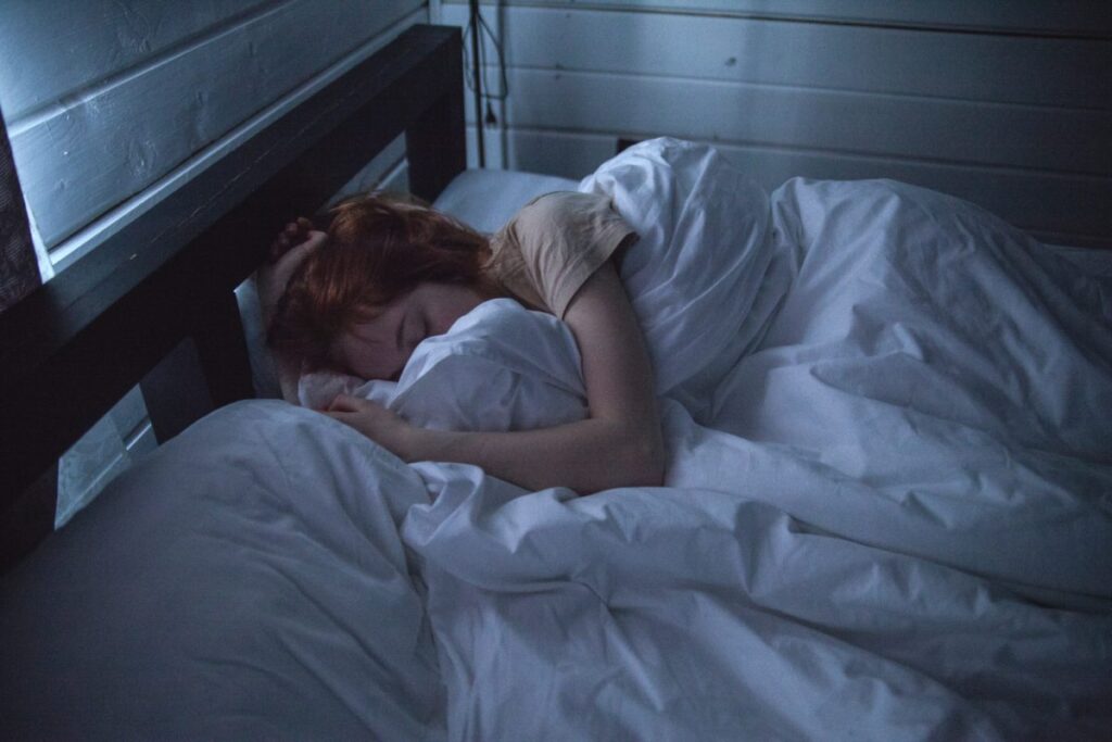 redhead girl sleep in her bed with white sheets