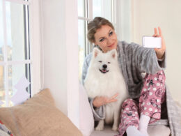 girl poses with white phone at home with pomeranian dog