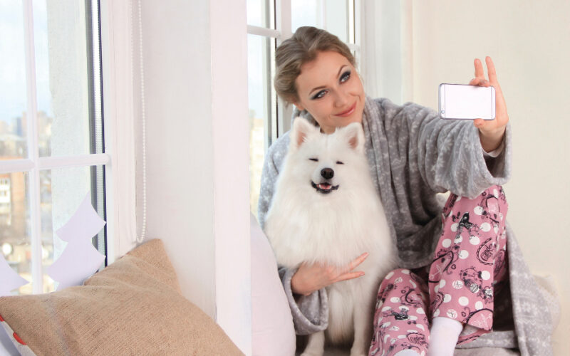 girl poses with white phone at home with pomeranian dog