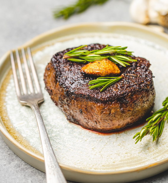 fancy meat dinner on plate with rosemary and fork