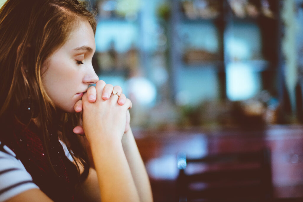 pensive girl sits with eyes closed and hands crossed looking upset or depressed