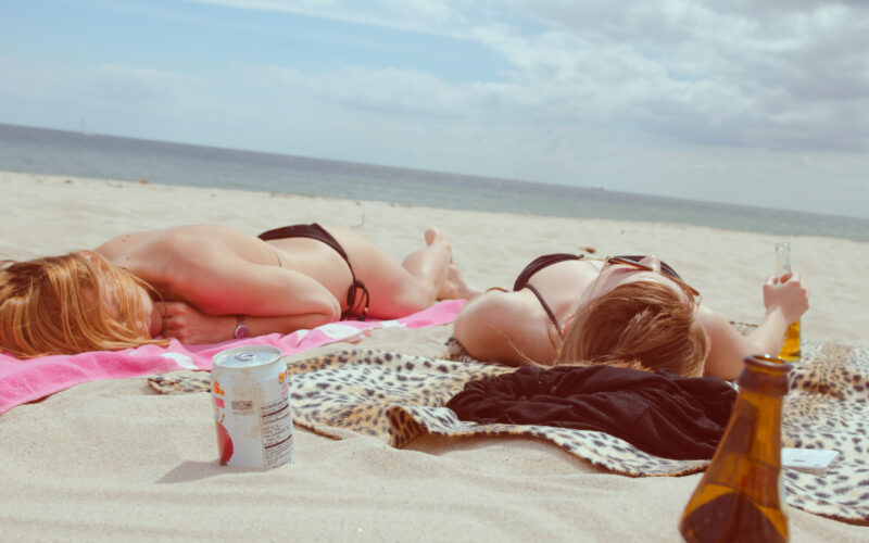 two girls lie in bikini bathingsuits on the sand on the beach