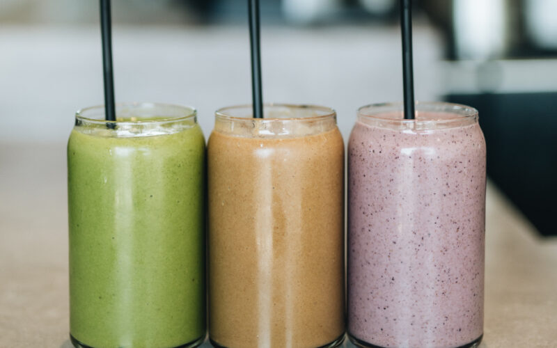 green, orange and purple smoothie drinks with straws found at some of the best smoothie shops in LA