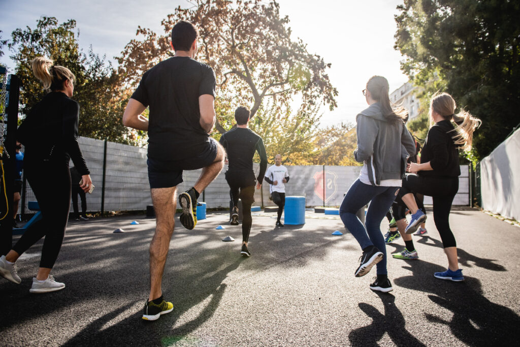 group of men and women get into some cardio outdoors during a group fitness session