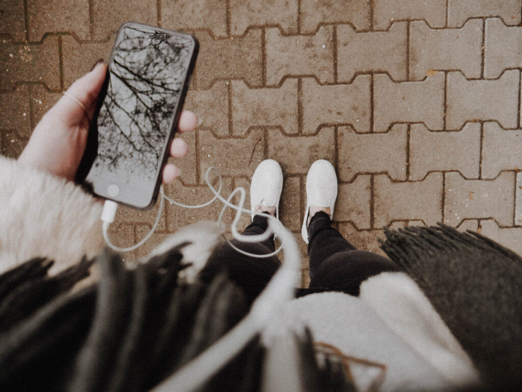 girl wearing scarf listens to headphones in cold weather on her iphone