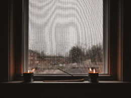 candles sit in front of a windowsill on a rainy day likely during winter or fall. calm and mellow