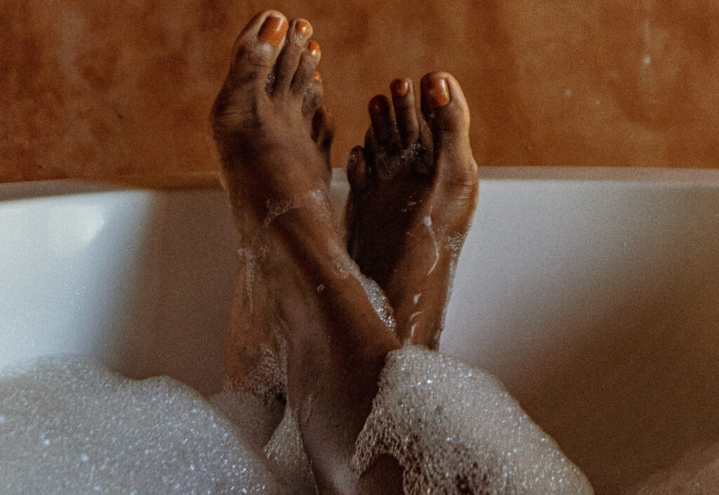 woman in bubble bath and painted pedicured toes relaxes in water