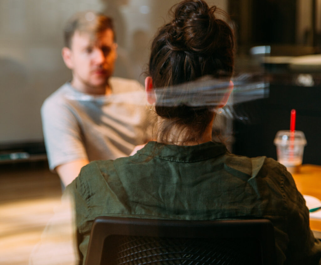 a man and woman sit across from each other talking at a table