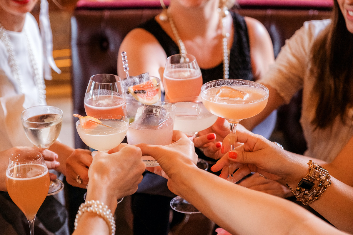 a handful of girlfriends toast with cocktails and wine to a fun night out