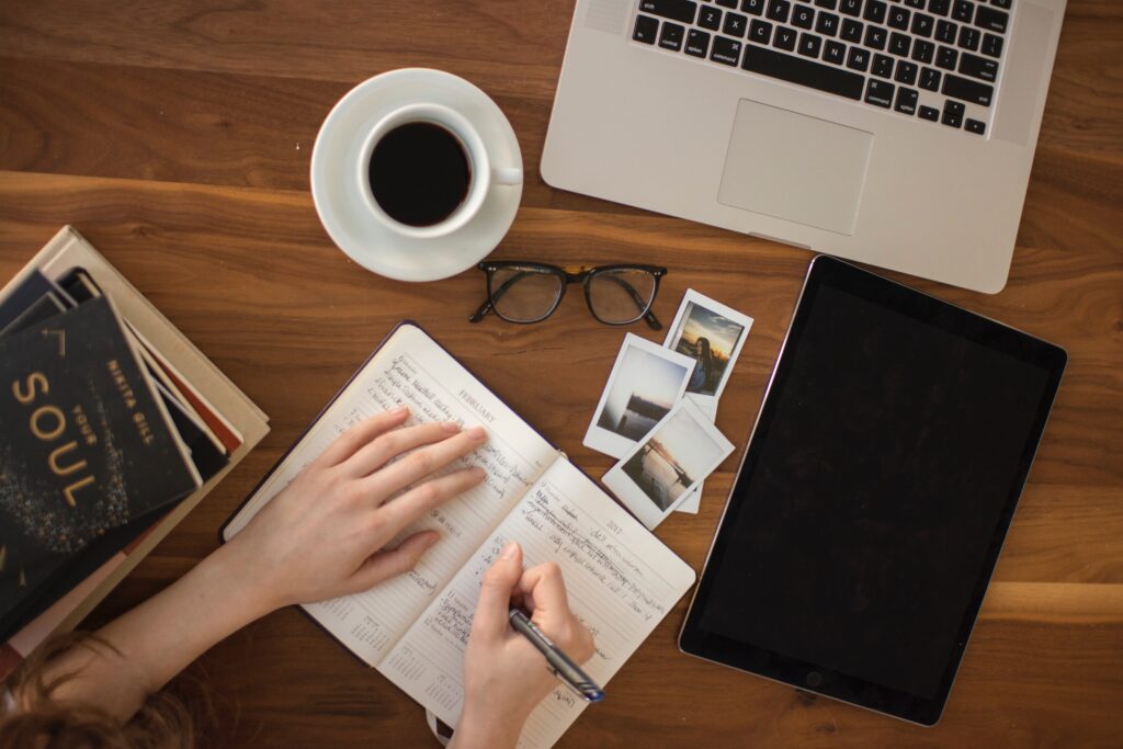 girl is journaling with coffee and computer in front of her